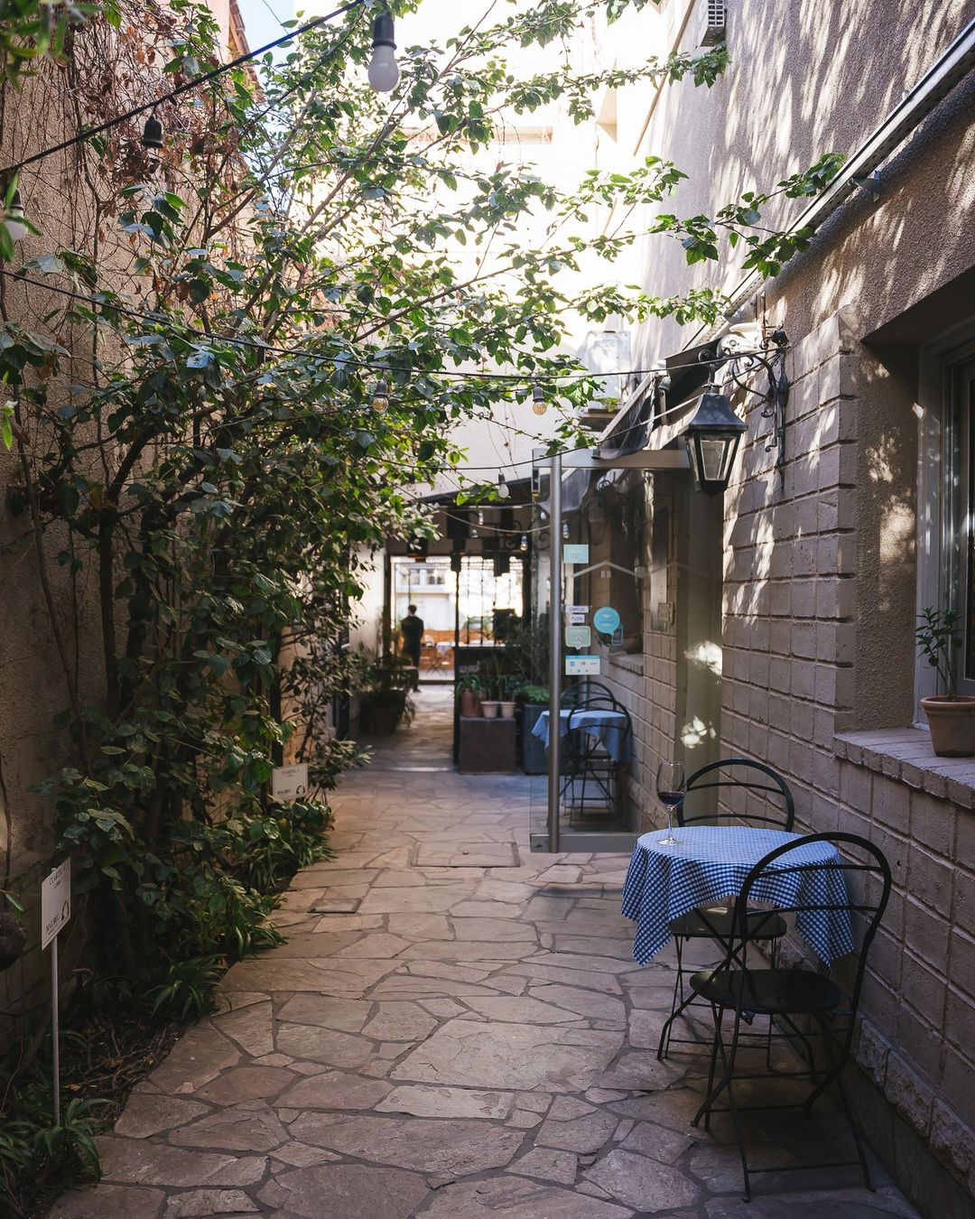 Entrada al restaurante, con mesas y plantas a su alrededor